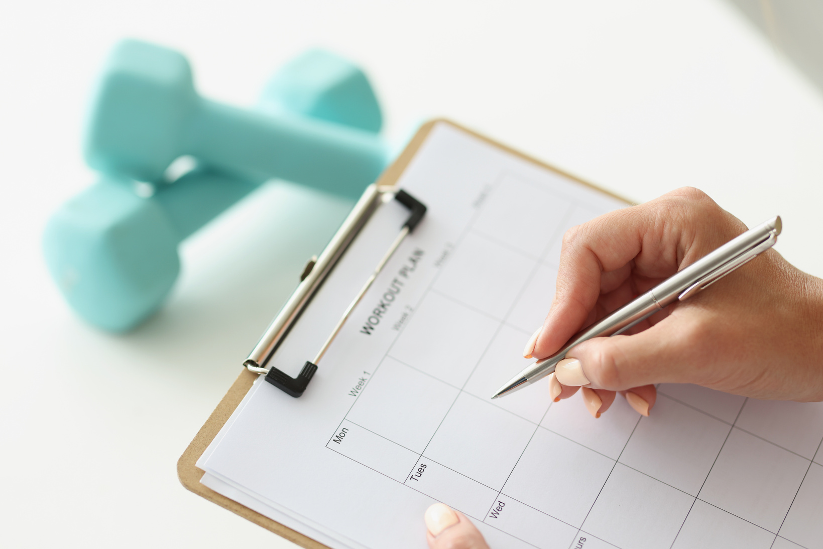 Woman Makes Workout Plan for Week Next to Dumbbells